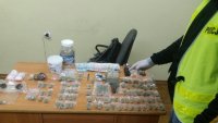 policjant zabezpieczający środki odurzające,  które spakowane są w foliowe woreczki i słoiki