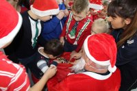 policjanci wraz ze Św. Mikołajem i dziećmi w trakcie spotkania profilaktycznego prowadzą pogadankę i rozdają upoinki