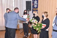 Komendanci wręczają kwiaty  podczas uroczystej zbiórki z okazji Święta Policji w auli wieluńskiej komendy