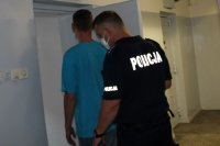 policjant prowadzi zatrzymanego do celi w PDOZ