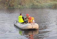 policjant i strażak przewożą odnalezionego zaginionego na pontonie