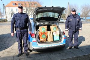 policjanci stoją przy otwartym bagażniku radiowozu, w którym znajdują się zebrane dary
