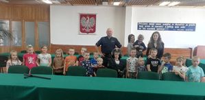 dzieci wraz z opiekunami i policjantem w auli komendy pozują do wspólnego zdjęcia