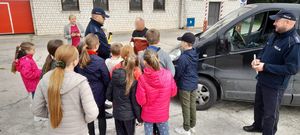 Dzieci wspólnie z policjantami prowadzą kontrolę drogową, kierowca wypija sok z cytryny.