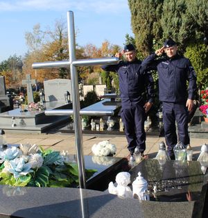 policjanci oddają honory przy grobie zmarłego