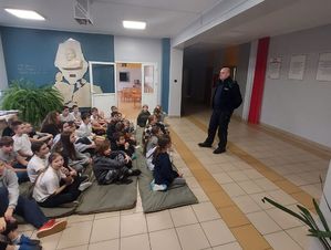 Policjant w szkole prowadzi pogadankę z dziećmi.