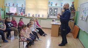 Policjant prowadzi prelekcje w sali lekcyjnej z uczniami.