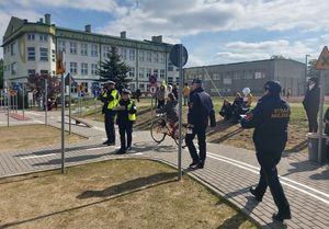 Zawodnik  na rowerze pokonuje przeszkodę na torze przygotowanym w ramach konkursu.  z boku stoją strażnicy miejscy i policjanci.