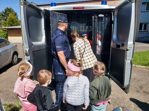 Policjant prezentuje dzieciom radiowóz.