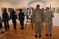 Zdjęcie przedstawiające salę w Muzeum Ziemi Wieluńskiej w trakcie Nocy Muzeów gdzie policjanci wystawili swoje stoisko z umundurowaniem i sprzętem policyjnym. Na zdjęciu odwiedzający stoisko goście.