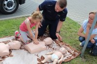 policjant prezentuje dzieciom zasady udzielania pierwszej pomocy przedmedycznej z wykorzystaniem fantoma