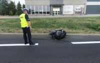 kolorowe zdjęcie przedstawiające policjanta oraz uszkodzony motocykl który brał udział w wypadku drogowym
