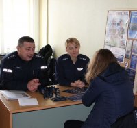 policjanci na stanowisku informacyjnym rozmawiają z osobami przychodzącymi do urzędu pracy i promują zawód policjanta