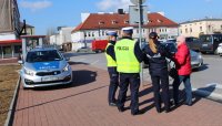 policjanci przy przejściu dla pieszych rozmawiają z przechodniami na temat bezpieczeństwa niechronionych uczestników ruchu drogowego wręczając odblaski