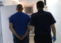 policjant prowadzi zatrzymanego do celi w PDOZ