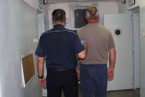 policjant prowadzi zatrzymanego