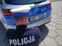 policjant ogląda zarysowanie na zderzaku radiowozu