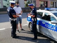 zdjęcie przedstawiające policjantów przekazujących maseczki ochronne mieszkańcom powiatu wieluńskiego
