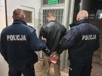 dwóch umundurowanych policjantów prowadzi zatrzymanego po korytarzu  w budynku Komendy Powiatowej Policji w Wieluniu