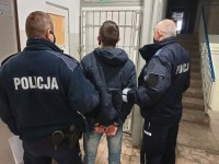 dwóch umundurowanych policjantów prowadzi zatrzymanego po korytarzu  w budynku Komendy Powiatowej Policji w Wieluniu