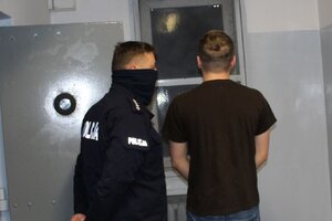umundurowany policjant prowadzi zatrzymanego do celi w pomieszczeniu dla osób zatrzymanych w wieluńskiej komendzie