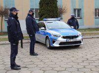 na parkingu przed budynkiem wieluńskiej komendy stoi zaparkowany oznakowany radiowóz oraz policjanci biorący udział w przekazaniu nowego pojazdu.