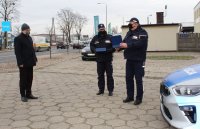 na parkingu przed budynkiem wieluńskiej komendy Komendant Powiatowy Policji  wraz z zastępcą  wręcza pamiątkową tabliczkę staroście.