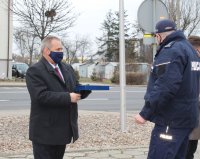 na parkingu przed budynkiem wieluńskiej komendy Komendant Powiatowy Policji  wraz z zastępcą  wręcza pamiątkową tabliczkę wójtowi.