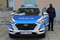umundurowany policjant stoi przy  radiowozie hyundai tucson , który zaparkowany jest przed budynkiem wieluńskiej komendy Policji