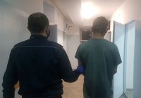 umundurowany policjant prowadzi zatrzymanego do celi w policyjnym areszcie