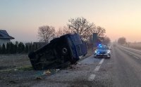 zdjęcie przedstawiające drogę , oznakowany radiowóz policyjny i samochód dostawczy, który leży przewrócony a bok w rowie.