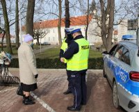 umundurowani policjanci wręczają pieszym kamizelki odblaskowe