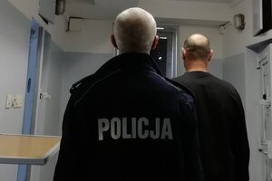 policjant prowadzi zatrzymanego do celi