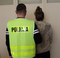 policjant nieumundurowany w kamizelce z napisem policja prowadzi zatrzymaną