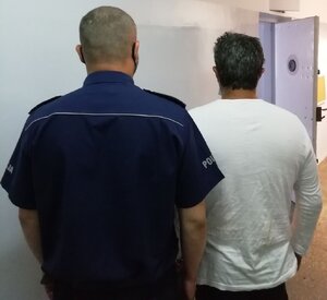 korytarz komendy, policjant prowadzi zatrzymanego mężczyznę