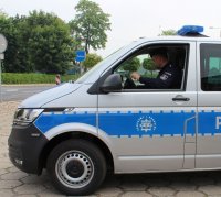 umundurowany policjant siedzący w radiowozie na miejscu kierowcy