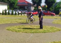 policjant  na terenie miasteczka ruchu drogowego przeprowadza egzamin praktyczny z jazdy rowerem