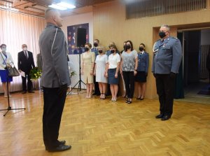 sala konferencyjna w wieluńskiej komendzie. Dowódca uroczystości składa meldunek Komendantowi Powiatowemu w Wieluniu. W tle uczestnicy uroczystości.