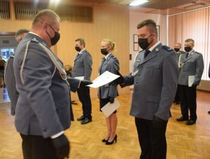 sala konferencyjna w wieluńskiej komendzie. Pododdział umundurowanych funkcjonariuszy mianowanych na wyższe stopnie policyjne. Komendant Powiatowy Policji w Wieluniu oraz jego zastępca wręczają akty mianowania.