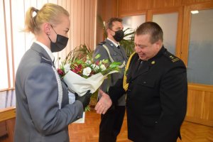 Dowódca Jednostki Ratownictwa Gaśniczego w Wieluniu wręcza wiązankę kwiatów policjantce.