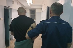 policjant prowadzi zatrzymanego do celi