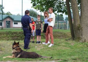 policjant z psem służbowy rozmawia z uczestnikami festynu na tematy bezpieczeństwa