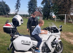 dziecko siedzi na motocyklu policyjnym obok stoi policjant