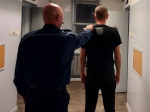 policjant prowadzi zatrzymanego mężczyznę do celi