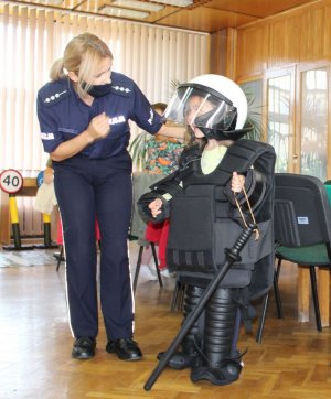 policjantka stoi obok dziecka ubranego policyjny  strój ochronny