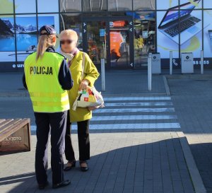 policjantka wręcza przechodniom kamizelki odblaskowe