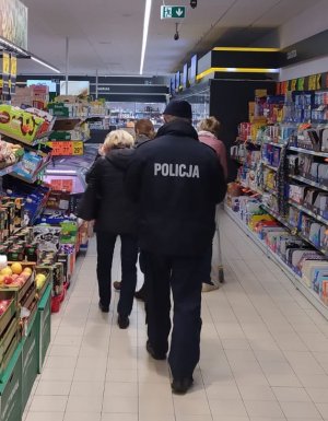 policjant z pracownikiem sanepidu idą przez sklep kontrolując przestrzeganie obostrzeń