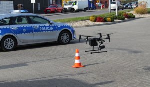 startujący dron, w tle radiowóz