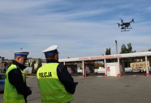 startujący dron, obok dwóch policjantów jeden z nich jest operatorem drona