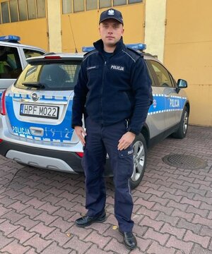 policjant stojący przed radiowozem